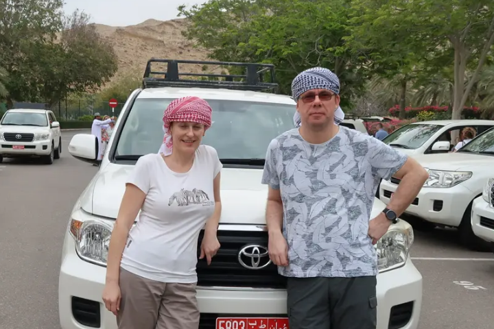 Boris and a woman posing in front of a white Toyota jeep outdoors