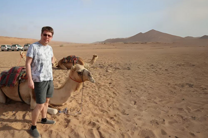 Boris posing with a camel in the desert