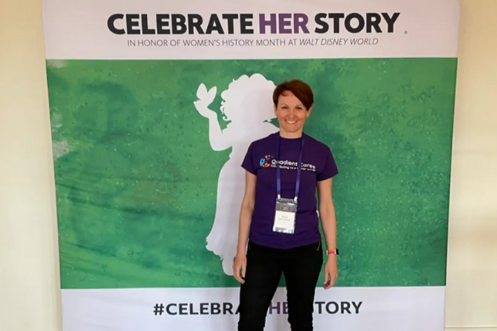 Katka in front of a 'Celebrate her story' wall print
