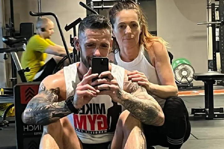 Maria and a man taking a mirror selfie at the gym
