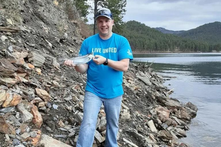 Nick by a lake holding a fish