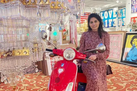 Fatima and a red Vespa in what looks like a modern museum